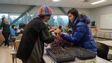 Two female students inspecting a plant within the classroom