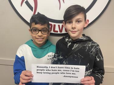 Two middle school students holding paper, smiling.