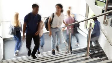 Motion Blur Shot Of High School Students Walking On Stairs Between Lessons In Busy College Building